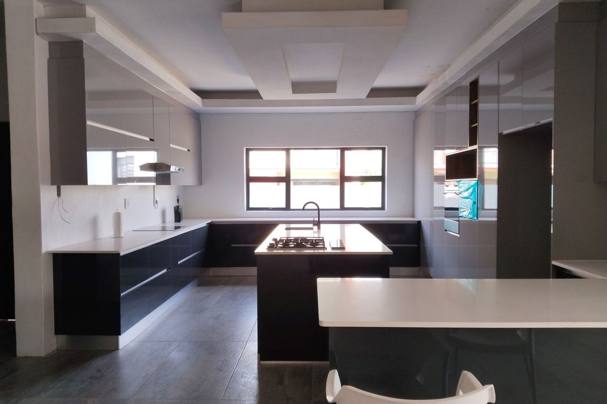 Modern, spacious kitchen featuring a central island with gas cooktop, sleek cabinetry, stone countertops, and recessed ceiling lighting.