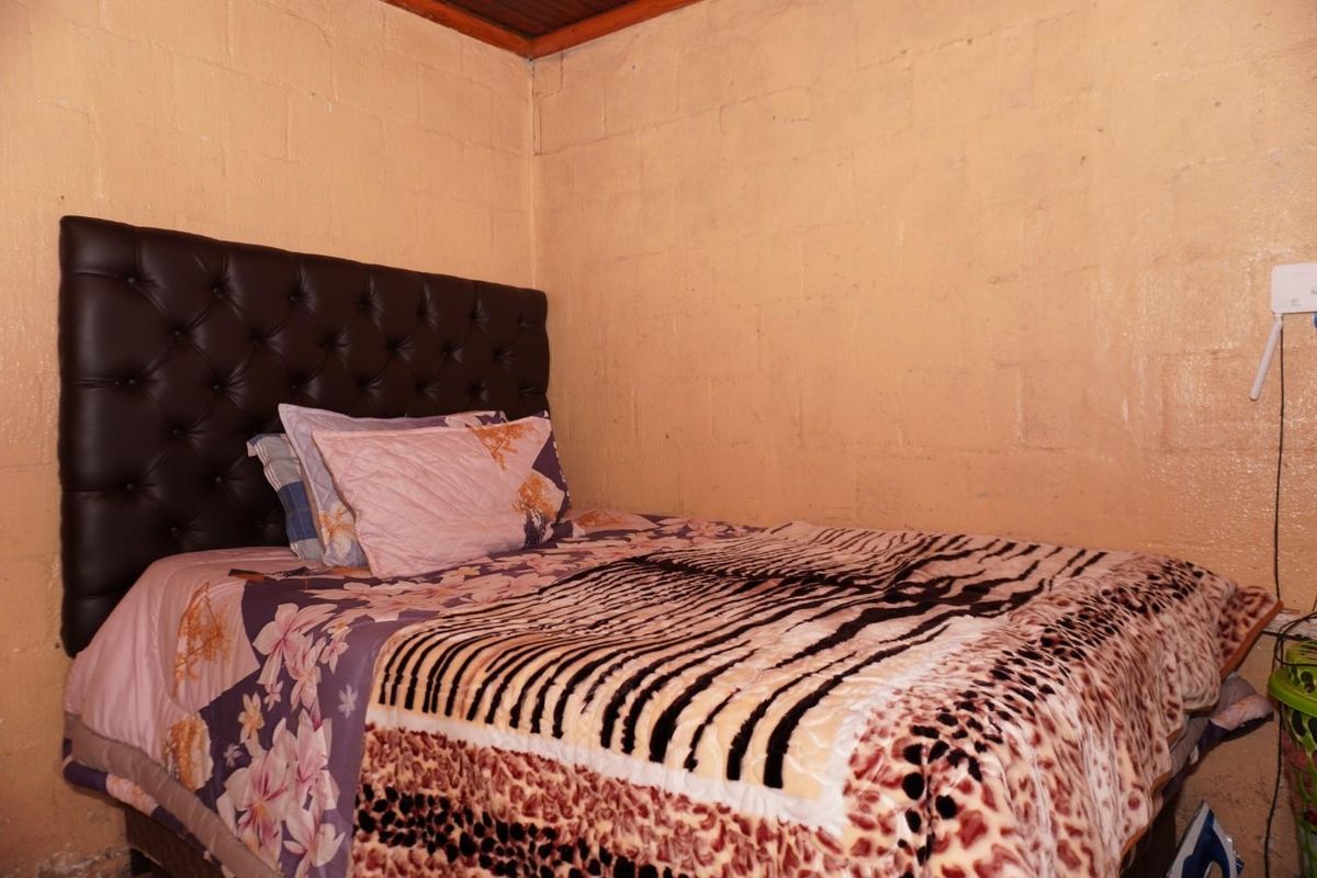 A bedroom featuring exposed concrete block walls and a timber-paneled ceiling, providing a rustic, unfinished aesthetic.