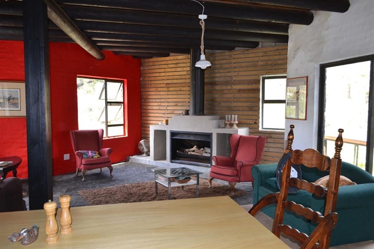 Rustic living room featuring exposed timber ceiling beams, a central built-in fireplace, and stone flooring, creating a warm and characterful farm-style atmosphere.
