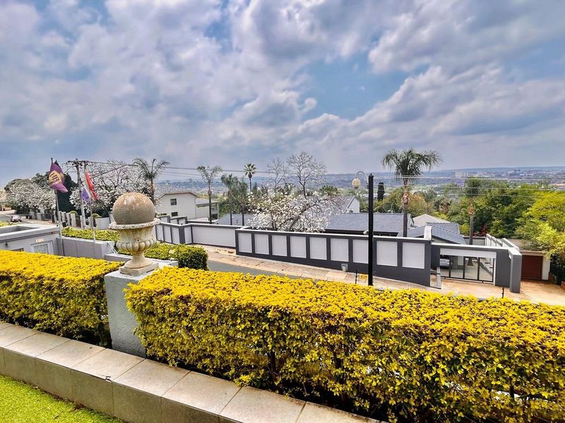 Elevated view overlooking the surrounding neighborhood and residential area, featuring manicured hedges and a stone boundary wall.