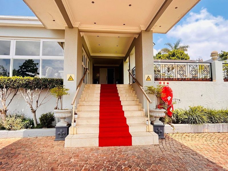 Grand entrance featuring a covered portico, stone staircase with handrails, and a paved driveway approach.