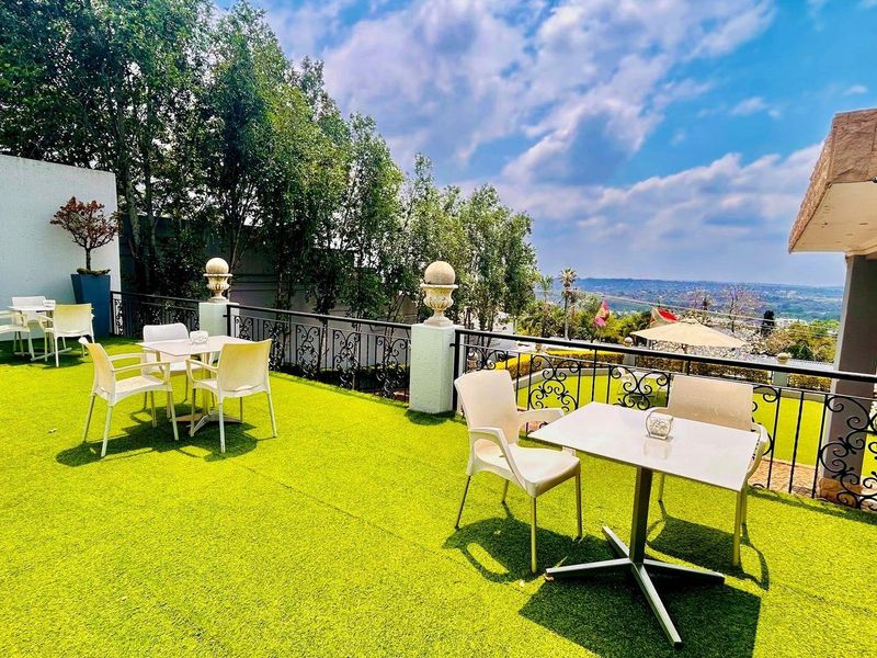 Spacious outdoor terrace featuring artificial turf flooring, decorative wrought iron railings, and expansive elevated views of the surrounding landscape.