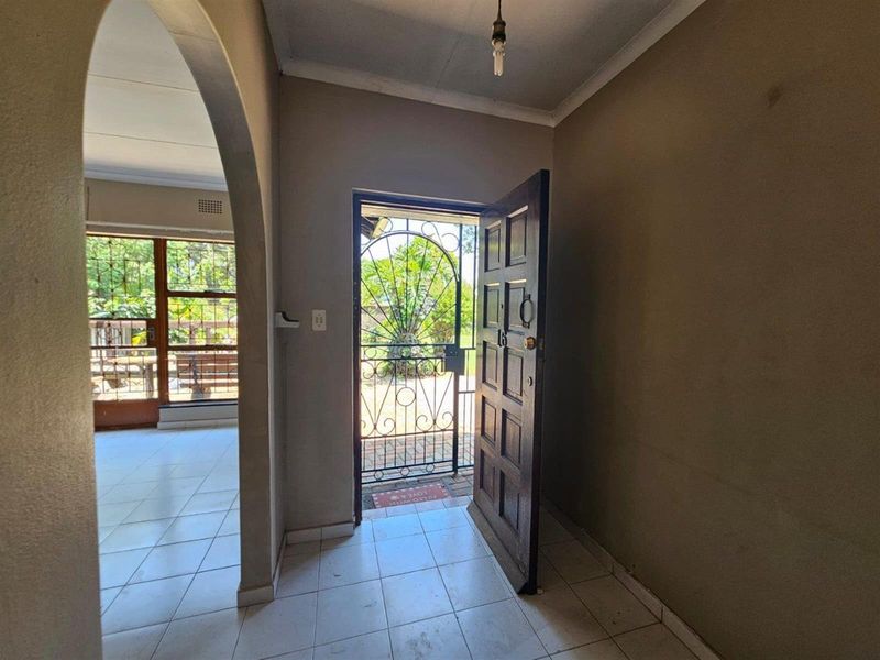 Entrance foyer featuring tiled flooring, an arched transition to the living area, and a secure metal gate leading to the exterior.
