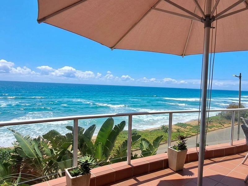 A spacious balcony featuring tiled flooring and a glass balustrade, offering panoramic ocean views.