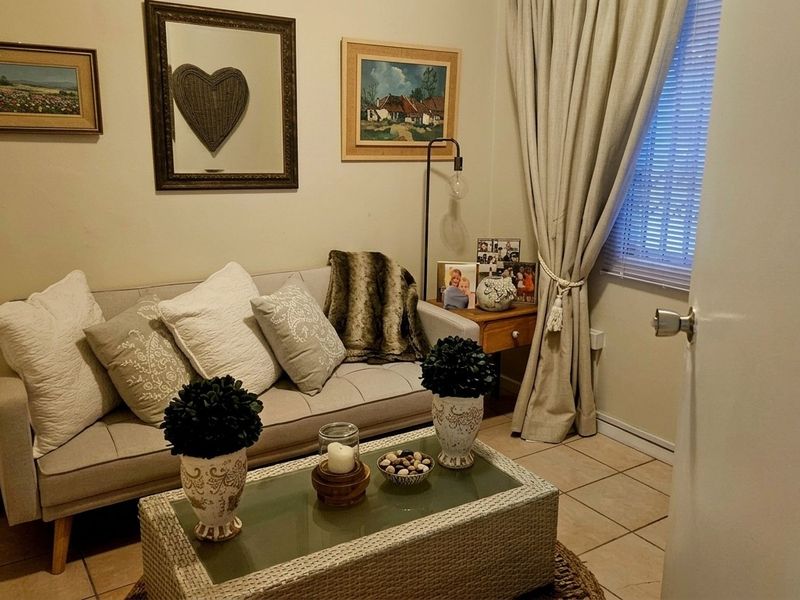 A cozy living room featuring tiled flooring and a window with fitted blinds and curtains, providing a comfortable and functional space.