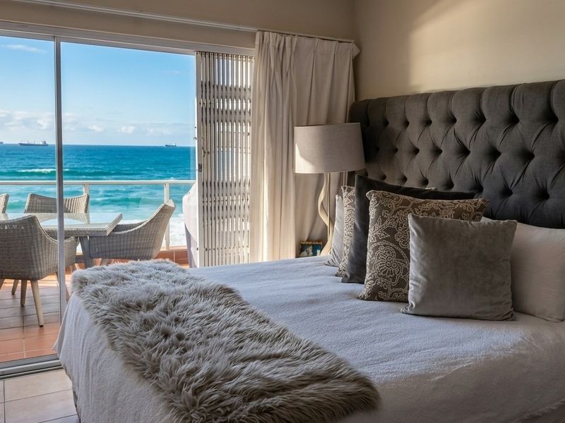 A well-appointed bedroom featuring large sliding glass doors that open onto a balcony with direct ocean views.
