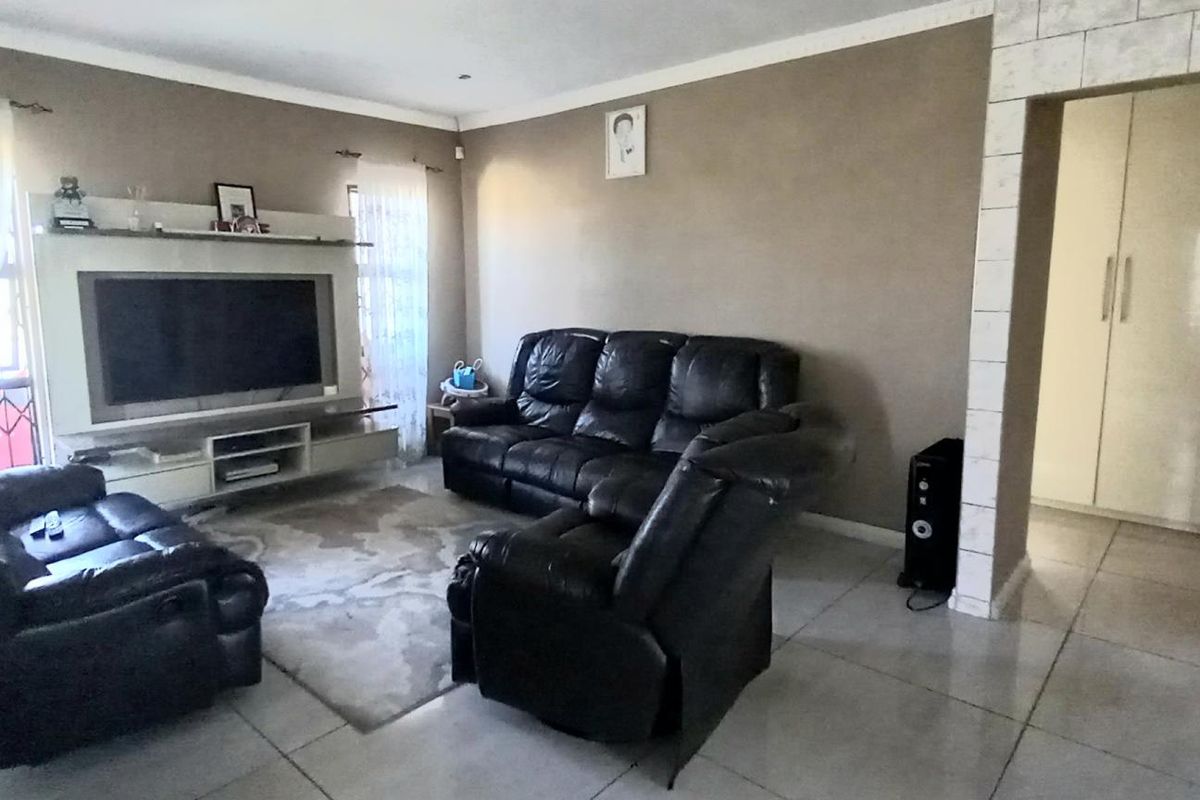 A spacious living room featuring tiled flooring, neutral wall tones, and a built-in media unit, providing a comfortable and functional living space.