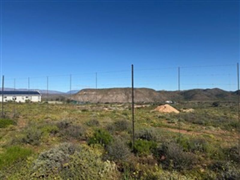 A vacant residential plot featuring wire perimeter fencing with scenic mountain views in the background.