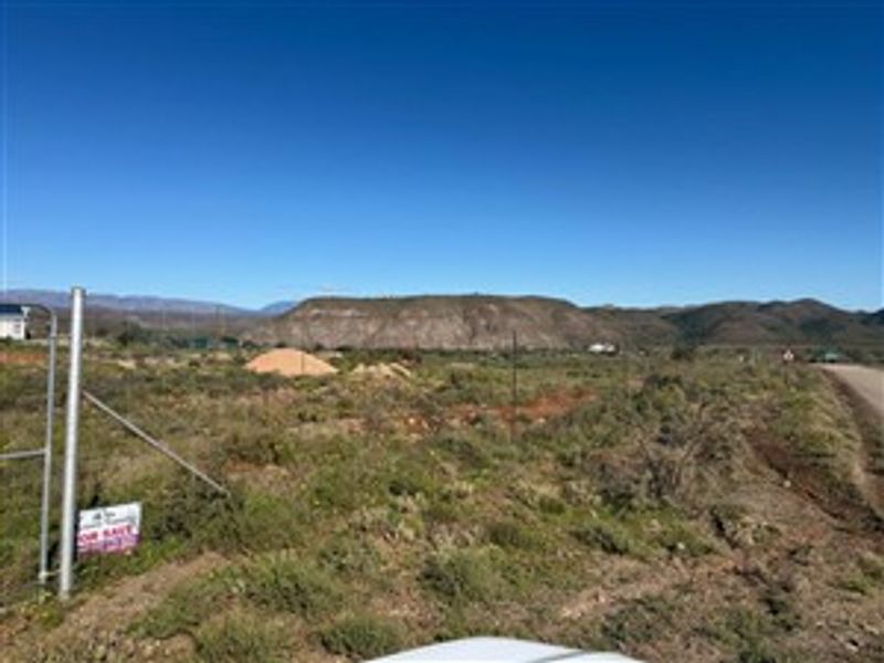 A vacant residential plot featuring natural landscape, perimeter fencing, and scenic mountain views, offering a blank canvas for development.