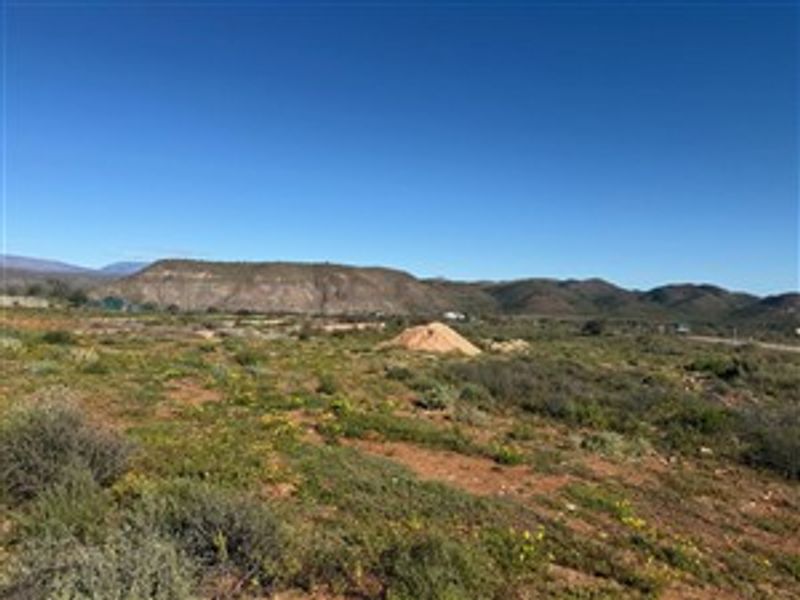 A wide-angle view of the vacant residential land featuring natural vegetation and scenic mountain vistas in the background.