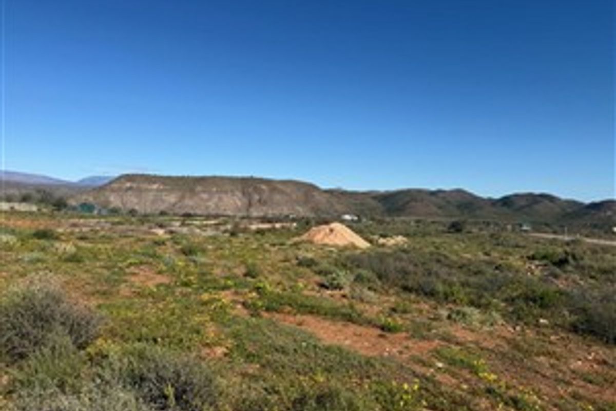 A wide-angle view of the vacant residential land featuring natural vegetation and scenic mountain vistas in the background.