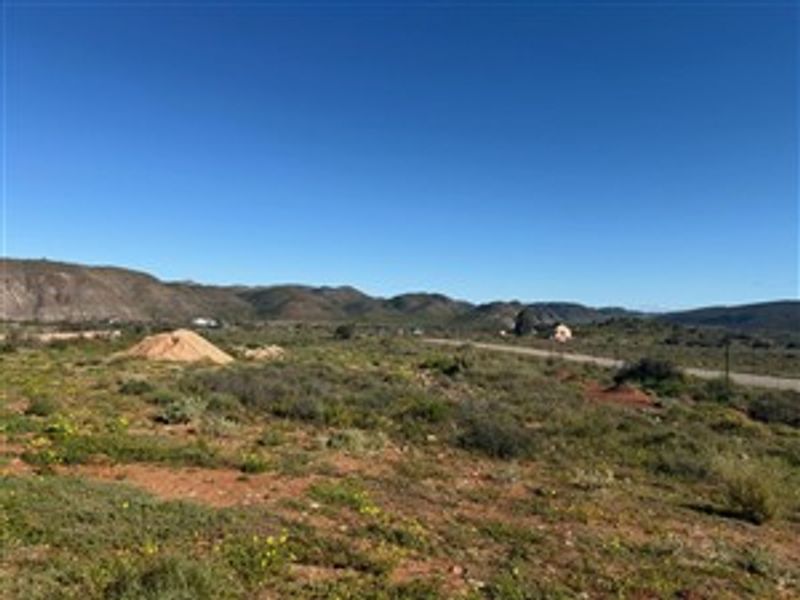 A wide-angle view of the vacant residential land featuring natural vegetation and distant mountain scenery.
