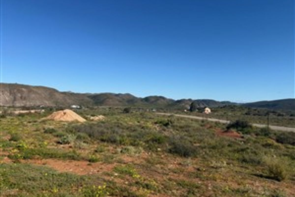 A wide-angle view of the vacant residential land featuring natural vegetation and distant mountain scenery.