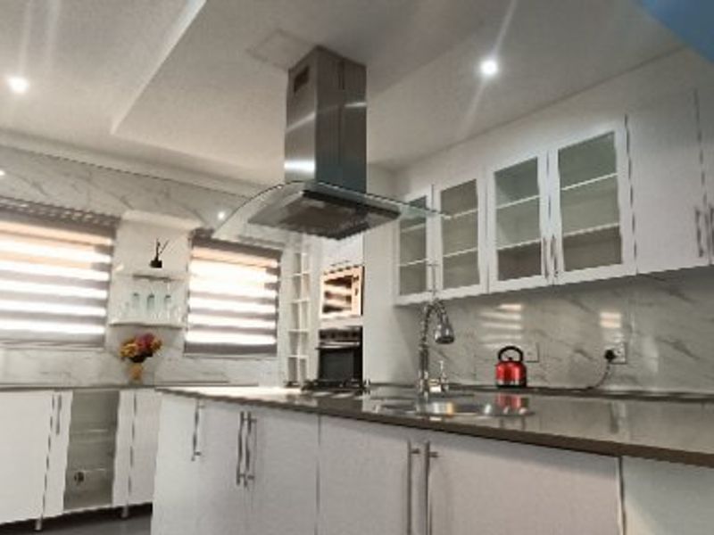 Modern kitchen featuring a central island, sleek white cabinetry, marble-look splashbacks, quartz countertops, and integrated stainless steel appliances.