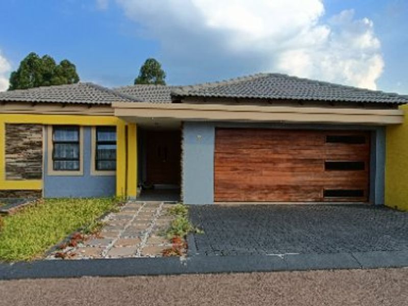 Front elevation of a modern house featuring a wooden garage door, stone cladding accents, a paved driveway, and a landscaped front garden.