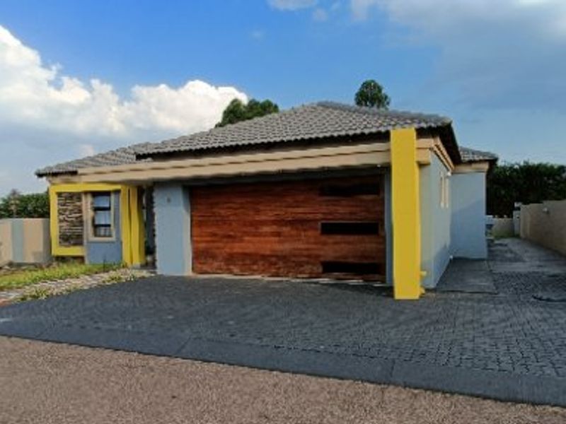 Front exterior view of a modern house featuring a wooden garage door, paved driveway, and decorative stone cladding on the facade.