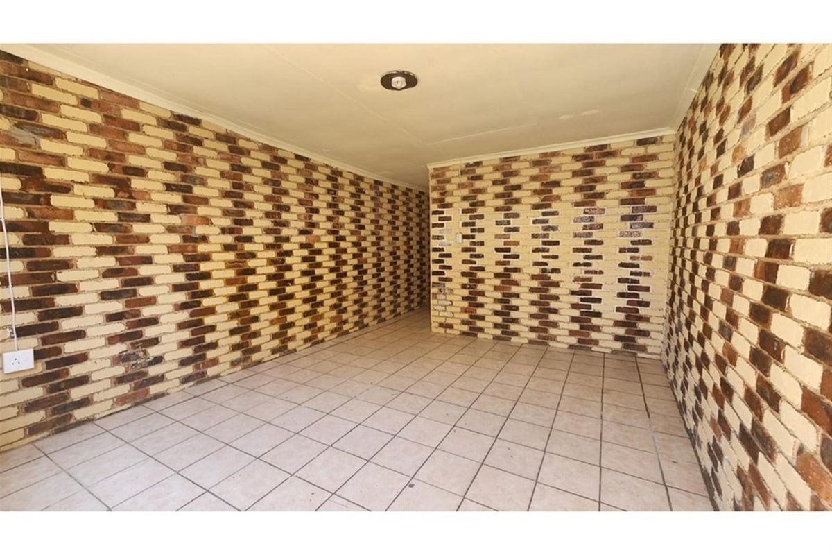An empty interior room featuring exposed face-brick walls and neutral ceramic floor tiling, suitable for a variety of living or utility purposes.