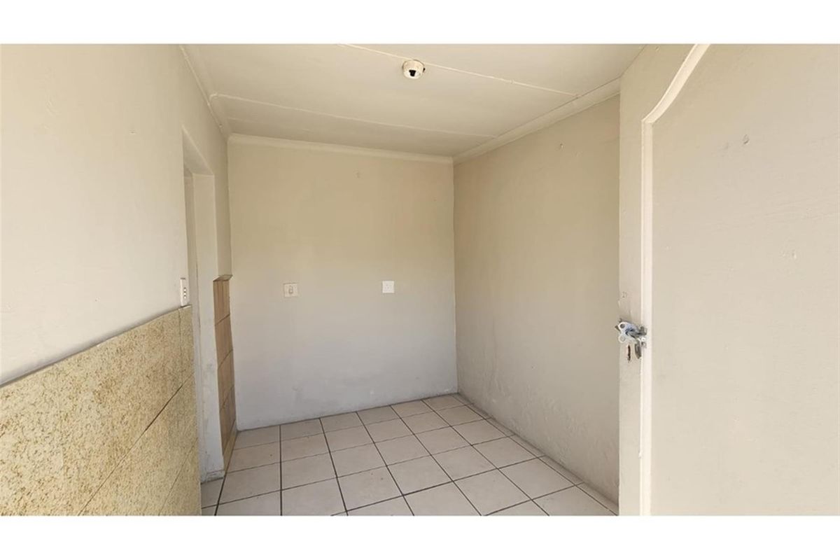 A functional utility space featuring tiled flooring and neutral wall finishes, suitable for laundry or storage purposes.
