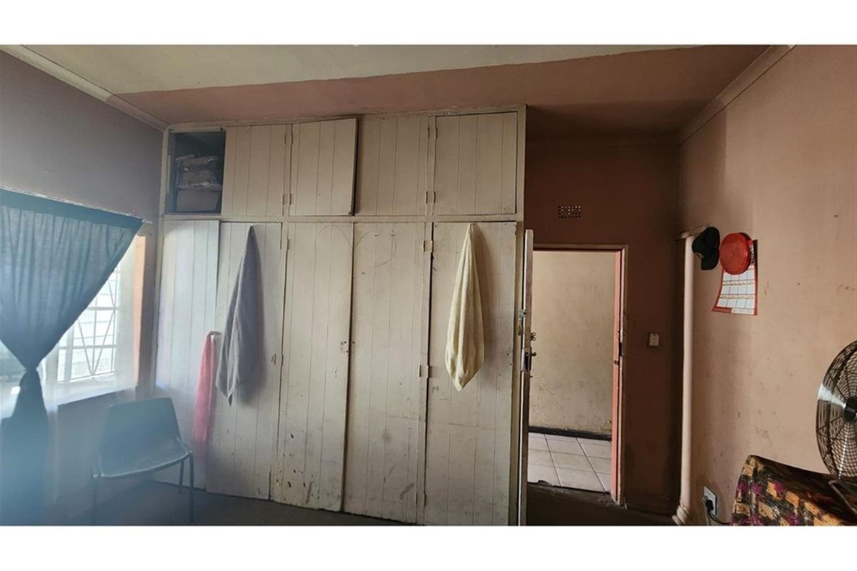 A bedroom featuring built-in wooden cupboards with overhead storage, providing functional storage space within the room.