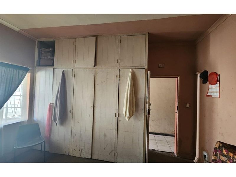 A bedroom featuring built-in wooden cupboards with overhead storage, providing functional storage space within the room.