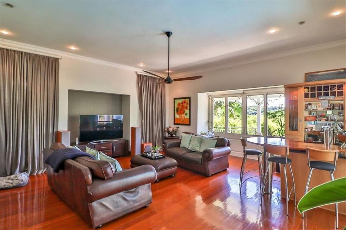 Spacious living room featuring polished hardwood floors, recessed lighting, a ceiling fan, and a built-in media alcove with direct access to the garden.
