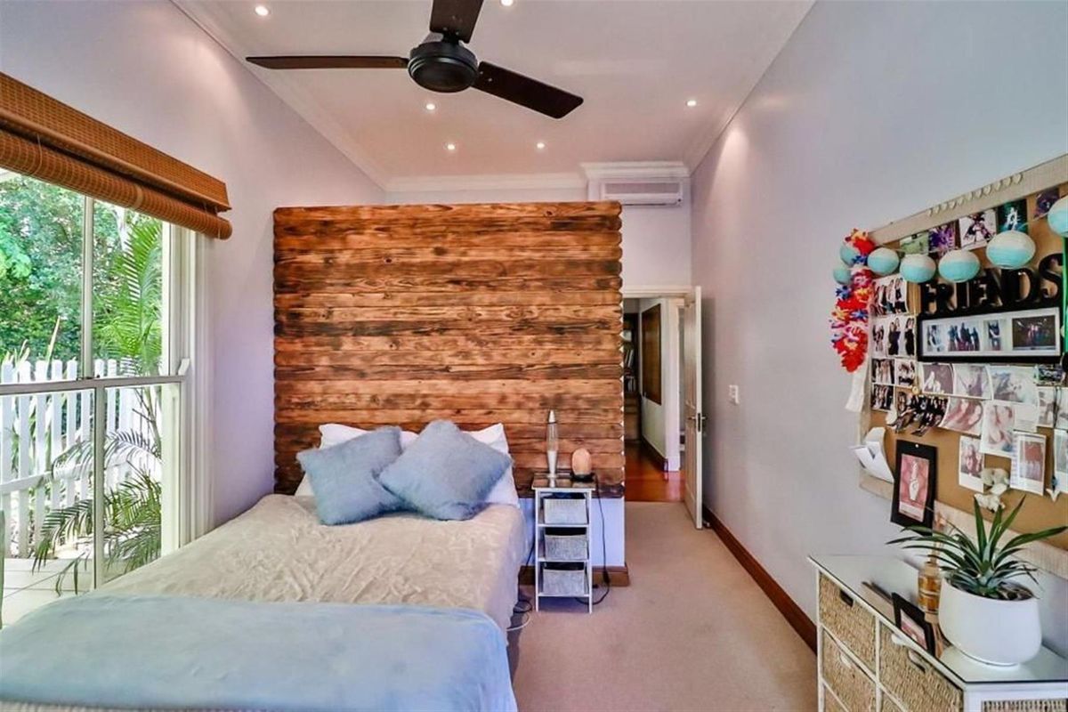 A well-maintained bedroom featuring a rustic timber feature wall, recessed ceiling lighting, a ceiling fan, and a split-system air conditioner.