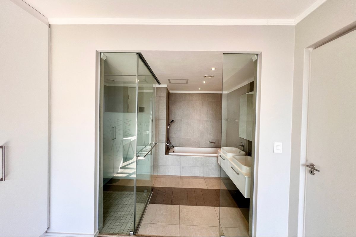 Modern bathroom featuring a glass-enclosed shower, a built-in bathtub, and a double vanity with contemporary fixtures and neutral tiling.