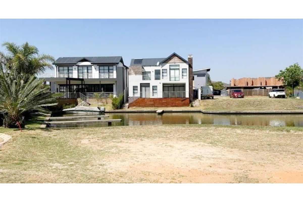 Rear view of modern waterfront residential properties featuring private jetties, timber decking, and multi-level balconies overlooking the canal.