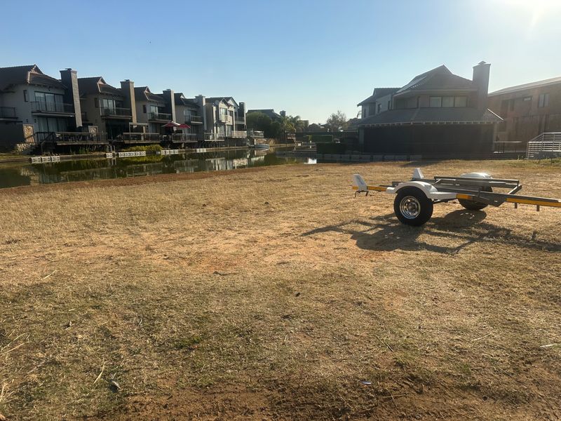 A vacant residential waterfront plot overlooking a canal, offering potential for a custom home build in a developed estate setting.