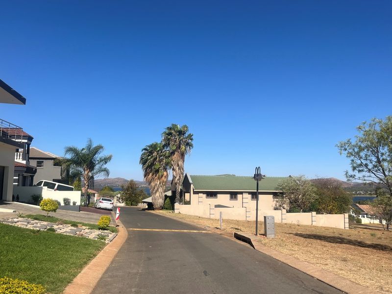 A view of a residential street in a developed estate, featuring paved roads, established landscaping, and surrounding residential properties.