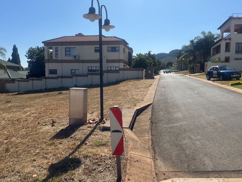 A view of a vacant residential plot situated along a paved street, featuring established boundary walls and existing utility connections.