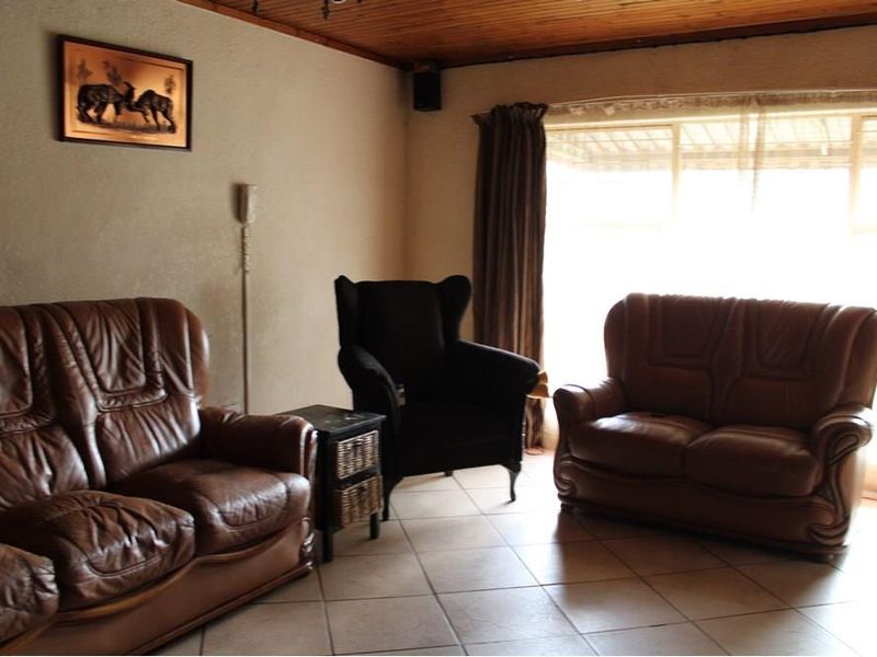 A living room featuring tiled flooring and a timber-paneled ceiling, with natural light entering through a large window.