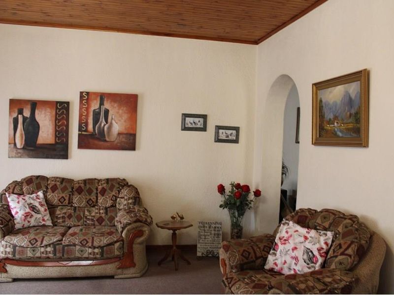 A living room featuring a timber-clad ceiling and an arched doorway leading to an adjacent space.