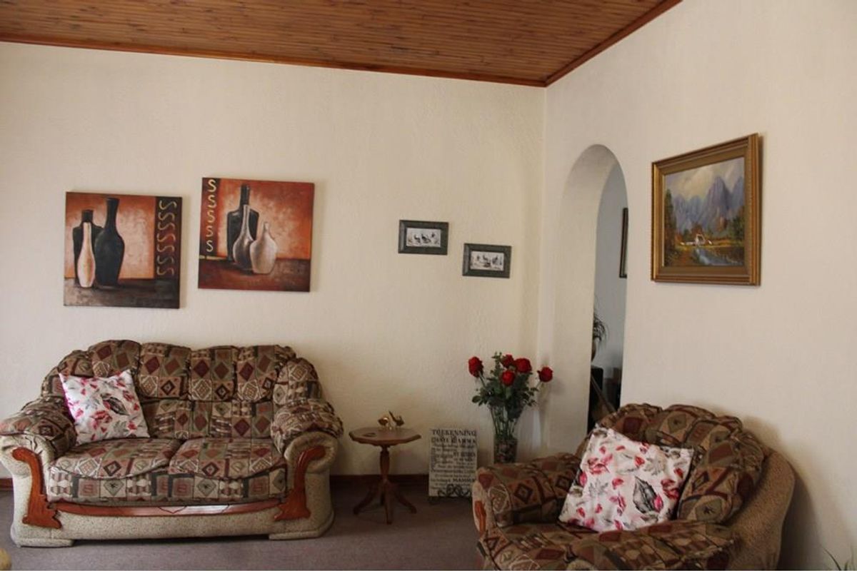 A living room featuring a timber-clad ceiling and an arched doorway leading to an adjacent space.