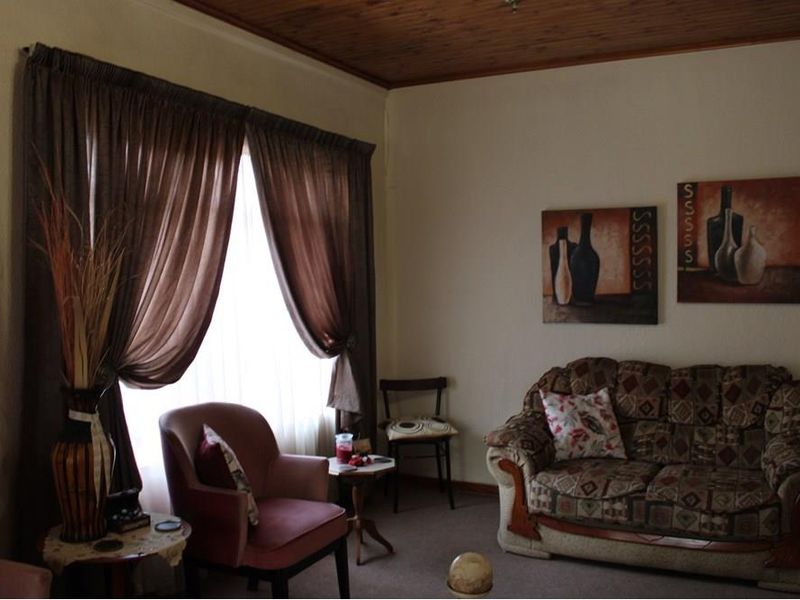 A living room featuring a timber-paneled ceiling and carpeted flooring, offering a traditional aesthetic with natural light through the window.