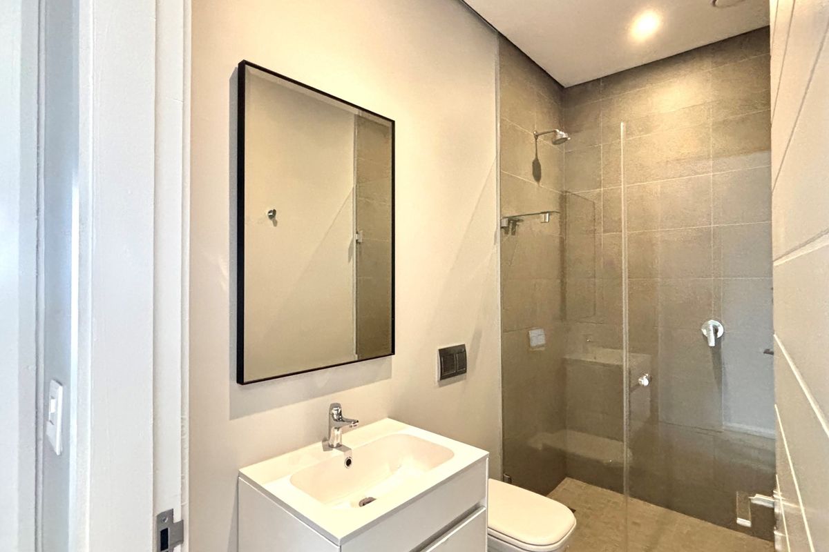 Modern bathroom featuring a sleek vanity with integrated basin, a frameless glass shower enclosure, and contemporary wall tiling.
