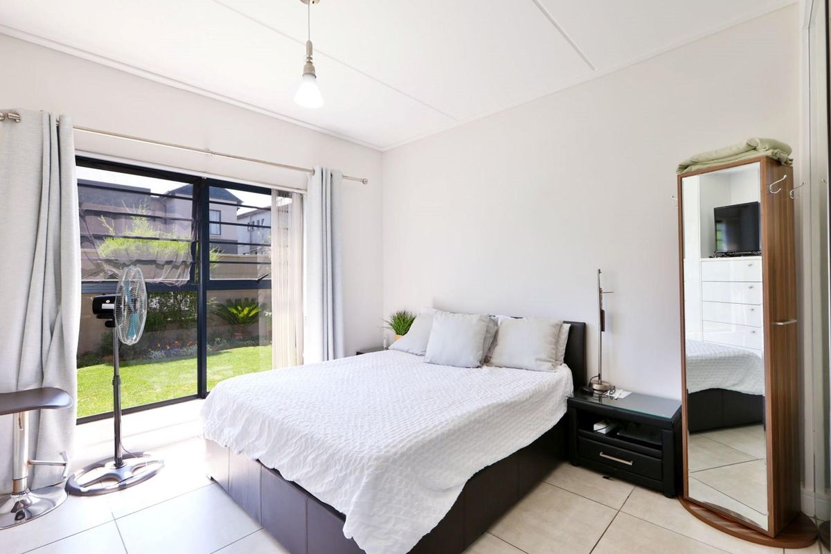 A bright bedroom featuring tiled flooring and a large sliding glass door providing direct access to the garden area.