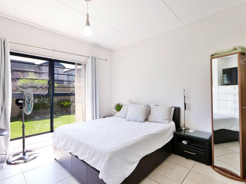 A bright bedroom featuring tiled flooring and a large sliding glass door providing direct access to the garden area.