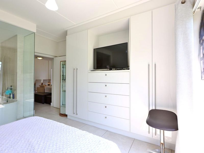 Modern bedroom featuring extensive built-in cabinetry with integrated shelving and a sleek glass-enclosed en-suite bathroom.