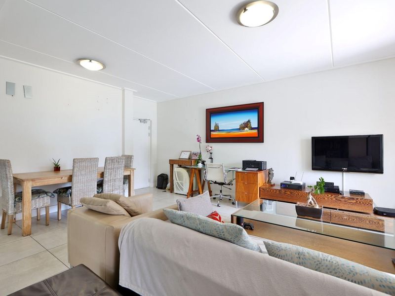 An open-plan living and dining area featuring neutral tiled flooring and simple flush mount ceiling lighting, providing a functional and versatile living space.