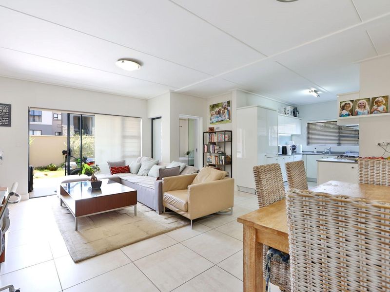 Open-plan living and dining area featuring tiled floors, a modern kitchen with built-in cabinetry, and direct access to an outdoor patio space.