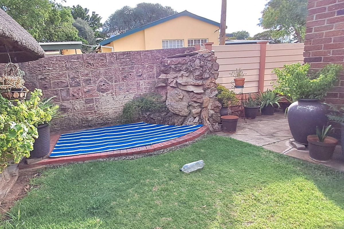 A private rear garden area featuring a natural stone feature wall, brick edging, and paved sections, providing a quiet outdoor space.