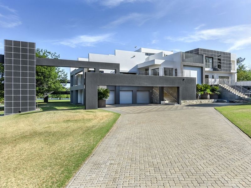 Modern architectural multi-level residence featuring a paved driveway, triple garage, and clean geometric lines with stone accents.