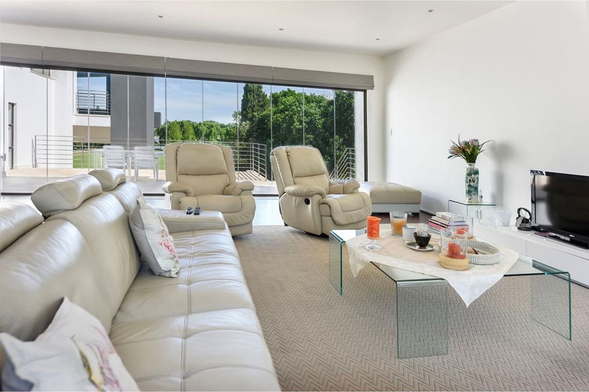 Spacious living room featuring large sliding glass doors that open onto an outdoor patio, providing ample natural light and garden views.