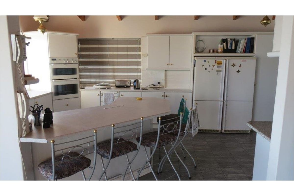 A functional kitchen featuring built-in double ovens, ample cabinetry, a breakfast bar, and tiled flooring, offering a practical layout for daily meal preparation.