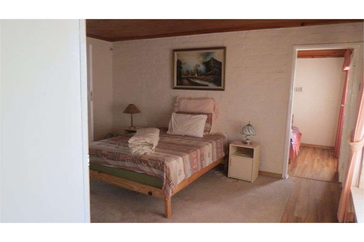 A bedroom featuring timber ceiling panels, carpeted flooring, and a doorway leading to an adjacent room.