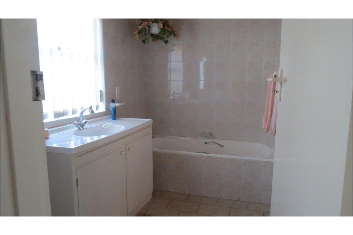 A functional bathroom featuring a built-in bathtub, tiled wall surrounds, and a vanity cabinet with an integrated sink.