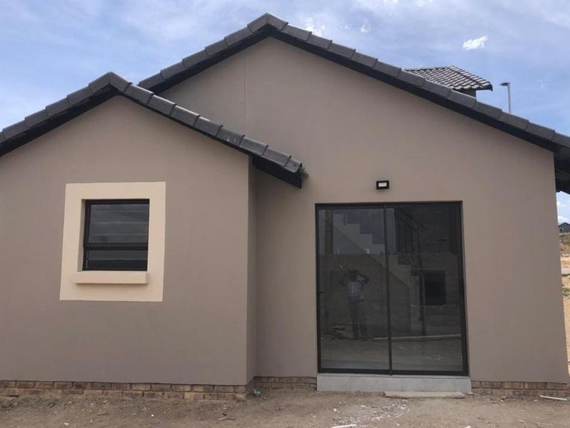 A modern single-story residential exterior featuring a neutral facade, dark tiled roof, sliding glass door, and framed window.