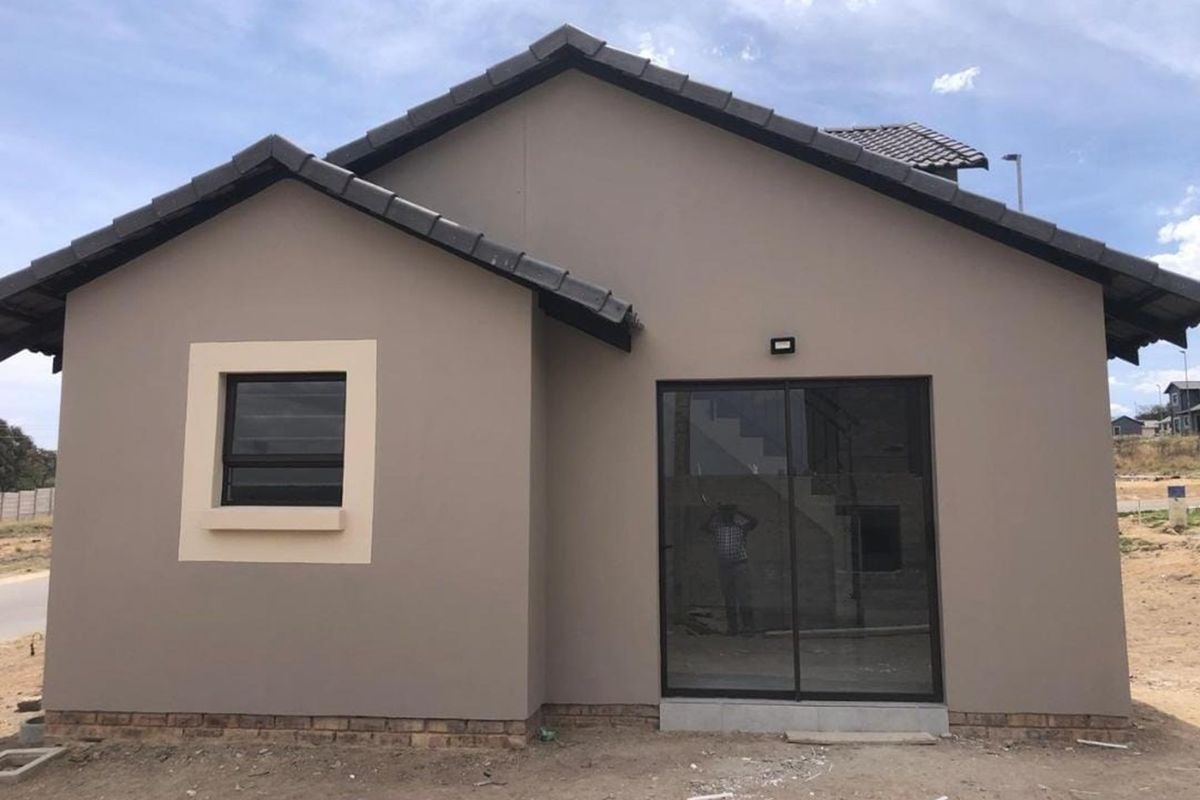 A modern single-story residential exterior featuring a neutral facade, dark tiled roof, sliding glass door, and framed window.