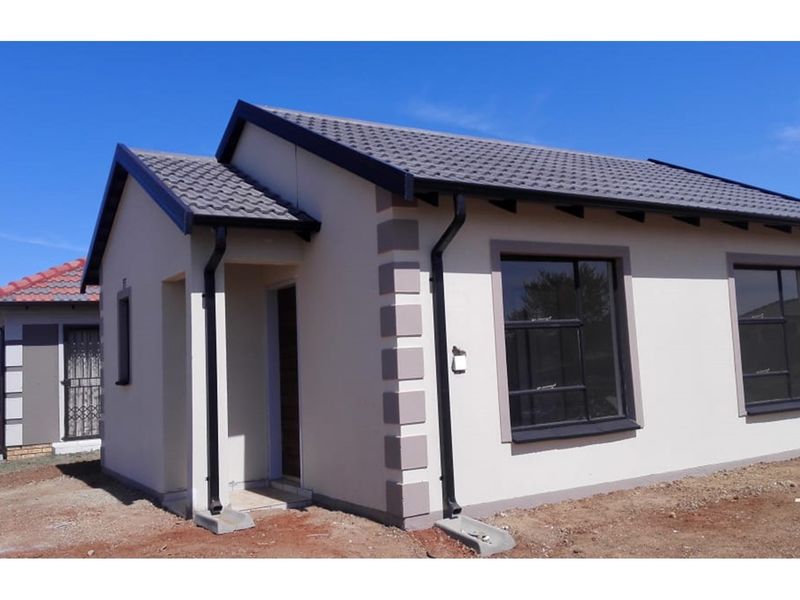 A modern single-story residential house featuring a tiled roof, painted exterior walls with decorative corner quoins, and black guttering.